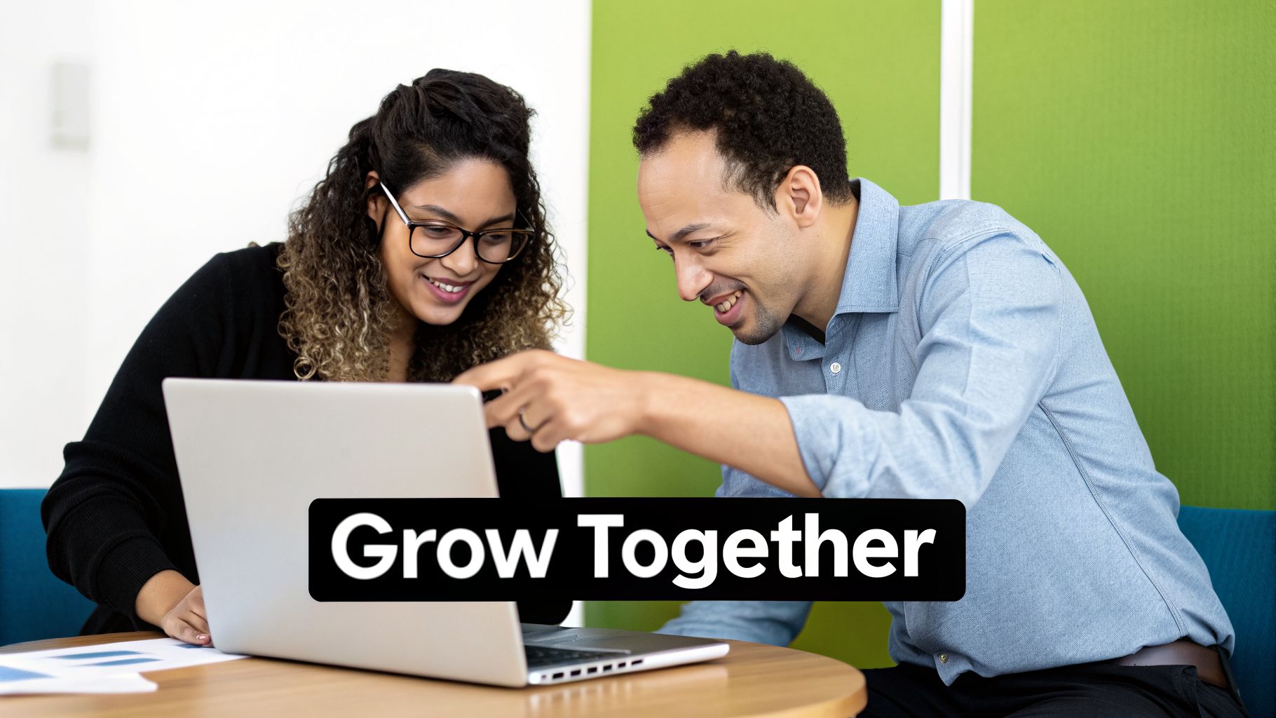 Two smiling colleagues, a man and a woman, collaborate on a laptop, with text 'Grow Together'.